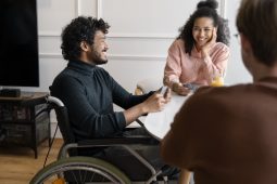 NDIS participant in a wheelchair smiling and talking with support workers during a community support meeting in Brisbane